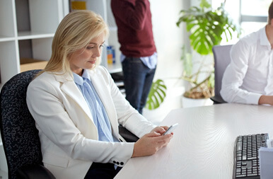 A clinic team member using her phone at a desk in a bright office