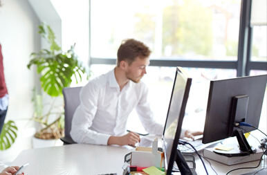 A colleague working at a computer in a sunlit office
